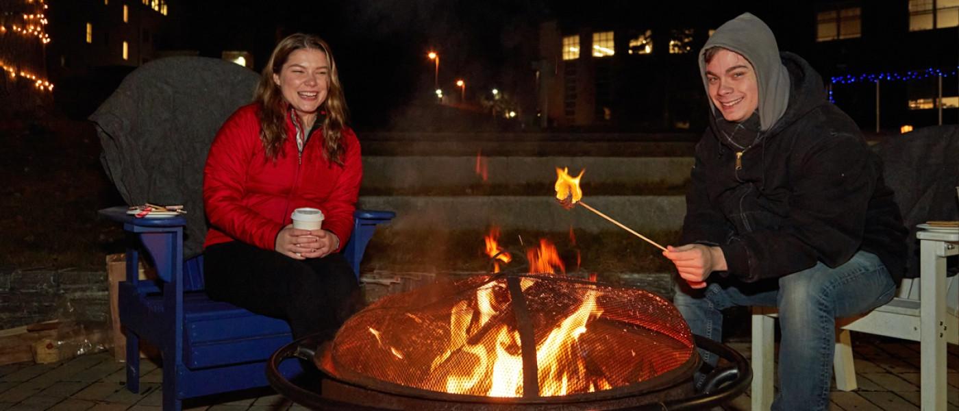 学生们在篝火旁烤棉花糖，喝热可可